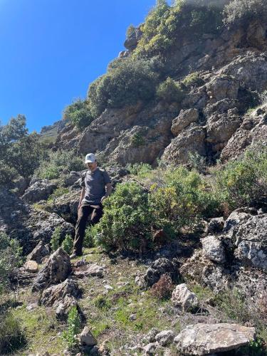 a man walking up a rocky mountain at Le Sommet Naturel in Chefchaouene