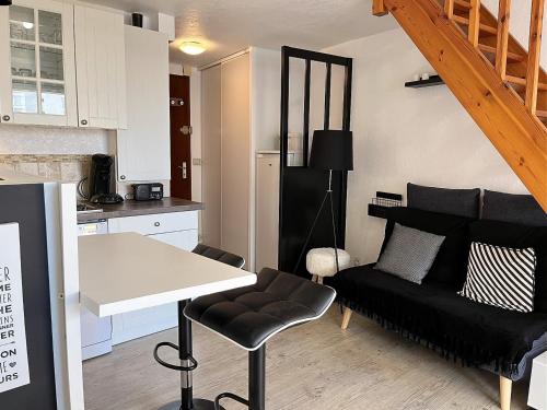 un salon avec un canapé noir et une table dans l'établissement Studio mezzanine proche mer avec balcon - FR-1-197-558, à Les Sables-dʼOlonne