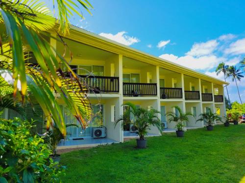 a yellow building with palm trees in front of it at Club Raro Resort- Adults Only in Rarotonga
