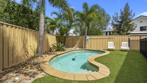 a swimming pool in a backyard with two chairs and a fence at Family Friendly House With Pool & Aircon in Woorim