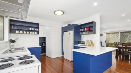 a kitchen with blue cabinets and a white refrigerator at Family Friendly House With Pool & Aircon in Woorim