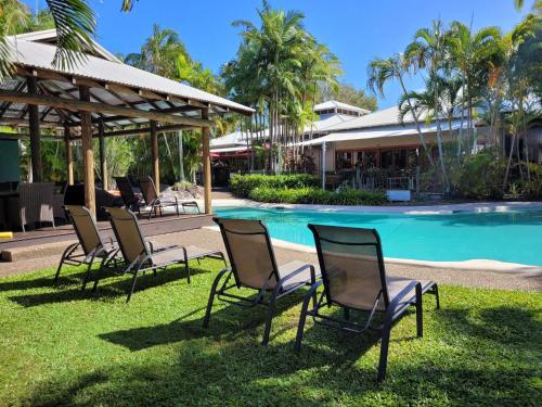 a group of chairs sitting in the grass by a pool at South Pacific Resort & Spa Noosa in Noosaville