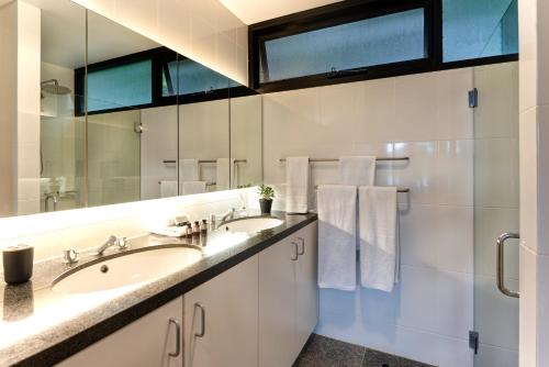 a bathroom with two sinks and a large mirror at Waves 6 on Hamilton Island by HIHA in Hamilton Island