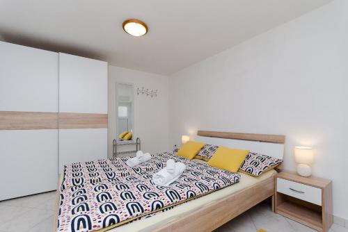 a white bedroom with a large bed with yellow pillows at House Marija in Mošćenička Draga