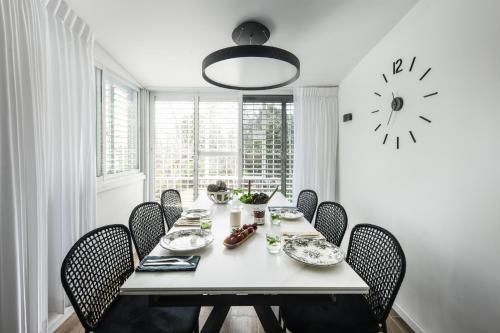 a dining room table with chairs and a clock on the wall at Chic 2BR Apt w Garden in Ramat Hasharon by Sea N' Rent in Ramat Hash Sharon