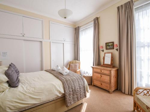 een slaapkamer met een bed, een dressoir en ramen bij Okanagan in Lyme Regis