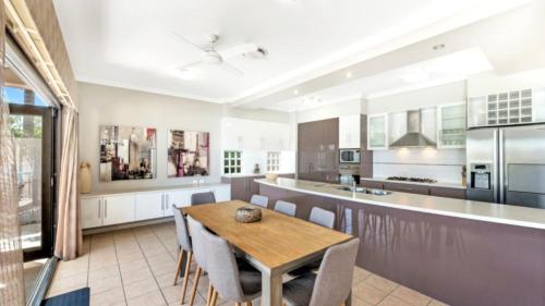 a kitchen with a wooden table and chairs at Spacious Canal Home With Pool in Banksia Beach