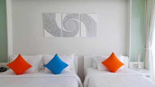 two white beds with colorful pillows in a room at Samui Resotel Beach Resort in Chaweng