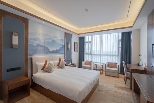 PengzeにあるS&N Xuanting Hotel Pengzeのベッドとデスクが備わるホテルルームです。