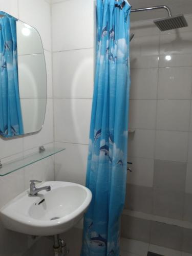 La salle de bains est pourvue d'un lavabo et d'un rideau de douche bleu. dans l'établissement 2-BR One Oasis Condo in CDO, à Cagayán de Oro