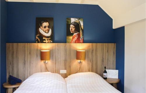 1 Schlafzimmer mit blauen Wänden und 1 Bett mit 2 Bildern in der Unterkunft Konijnenbult in Ommen