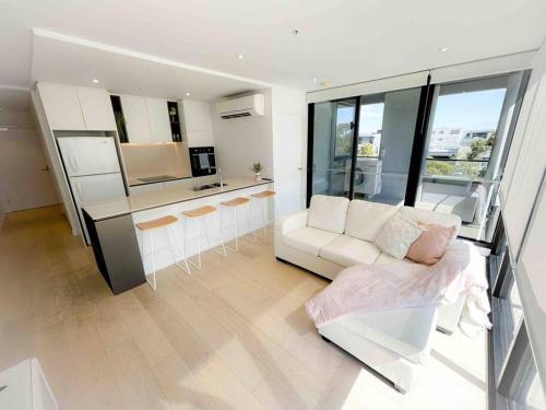 a living room with a white couch and a kitchen at Moonee Ponds Stylish Apartment - 415 in Melbourne