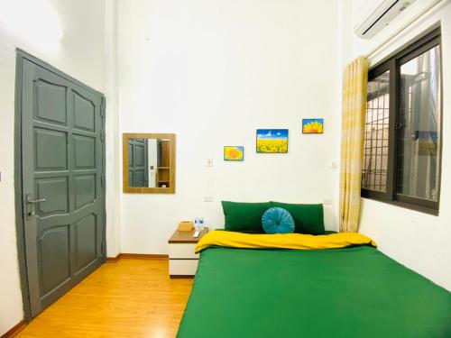 a bedroom with a green and yellow bed and a door at Hanoi Sunrise Homestay Long Biên in Hanoi