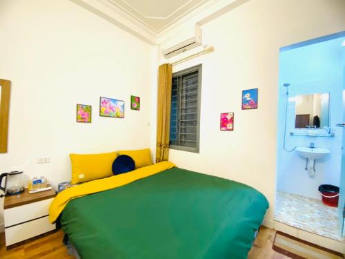 a bedroom with a green and yellow bed and a sink at Hanoi Sunrise Homestay Long Biên in Hanoi