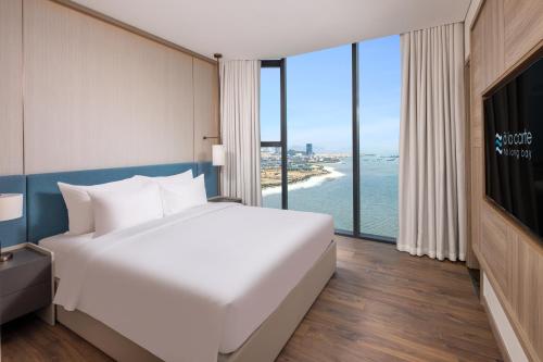 a bedroom with a bed and a view of the ocean at A La Carte Ha Long Bay Managed by TASECO in Ha Long