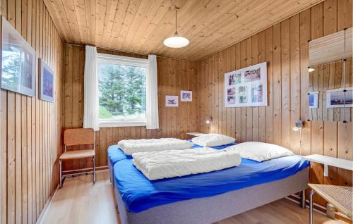 a bedroom with a blue bed in a wooden wall at Lovely Home In Thisted With House A Panoramic View in Thisted