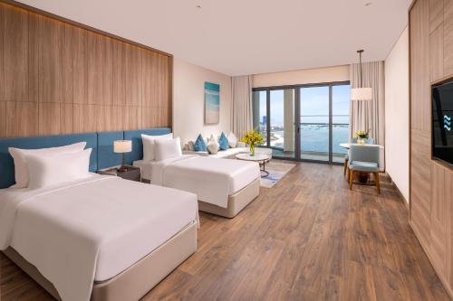 um quarto de hotel com duas camas e um sofá em A La Carte Ha Long Bay Hotel em Ha Long