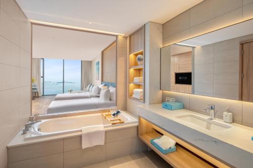 een badkamer met een bad en een bed in een kamer bij A La Carte Ha Long Bay Hotel in Ha Long