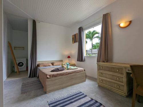 ein Schlafzimmer mit einem Bett, einer Kommode und einem Fenster in der Unterkunft Charmante villa créole climatisée, jardin tropical et piscine privés in Lamentin