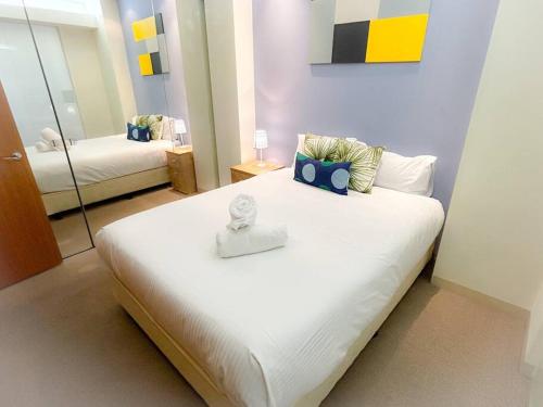 a bedroom with a large white bed and a mirror at Melbourne City Central Apartment - 296 in Melbourne