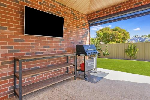 a brick wall with a grill and a tv at Tranquil Retreat Busselton in Geographe