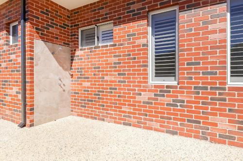 a brick wall with a door and two windows at Tranquil Retreat Busselton in Geographe