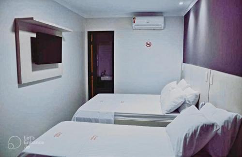 a hotel room with two beds and a tv at Hotel Center in Feira de Santana