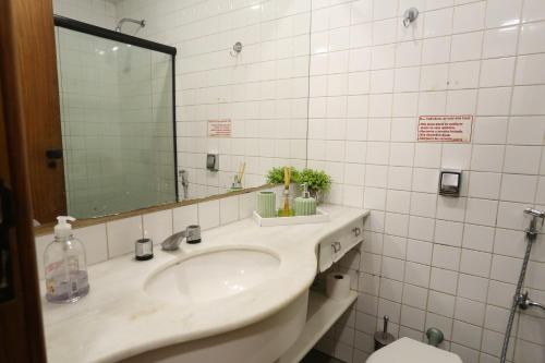 W łazience znajduje się umywalka, lustro i toaleta. w obiekcie Pituba 1Q frente ao mar Ed Madison Plaza 100m da praia w mieście Salvador