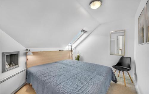 a white bedroom with a bed and a chair at Klitten in Søndervig