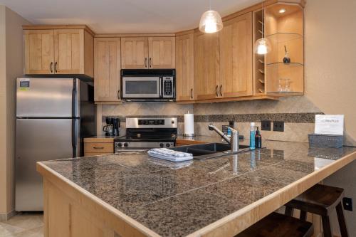 uma cozinha com um balcão de granito e um frigorífico em Iron Horse C5083 condo em Winter Park
