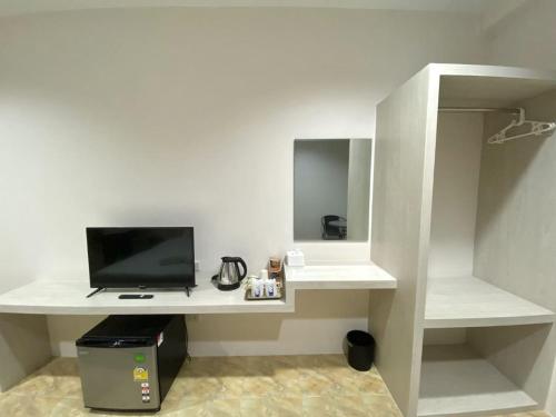 Habitación con escritorio blanco y TV. en บ้านสายสิริ, en Ban Bang Talat