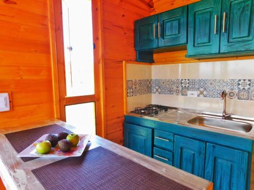 una cocina con armarios azules y una bandeja de fruta en Cabaña con vista a la laguna de Tota, en Tota