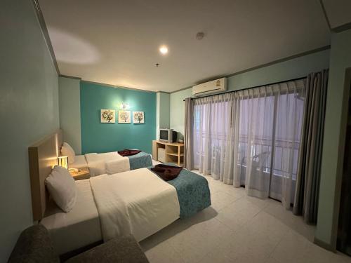 a hotel room with two beds and a window at Thipurai City Hotel in Hua Hin