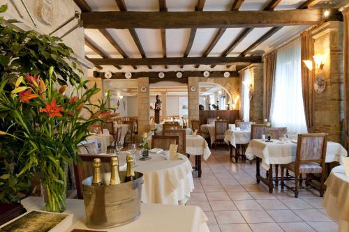 un restaurante con mesas blancas, sillas y flores en Logis Le Cheval Rouge en Sainte-Menehould