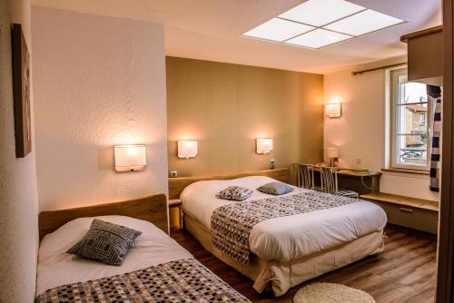 um quarto de hotel com duas camas e uma janela em Logis Le Cheval Rouge em Sainte-Menehould