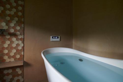 a bath tub in a bathroom with a clock on the wall at Shirafuji in Suzaka