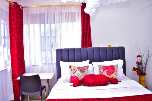 Schlafzimmer mit einem Bett mit roten Vorhängen und einem Tisch in der Unterkunft Rozy Penthouse in Kisumu