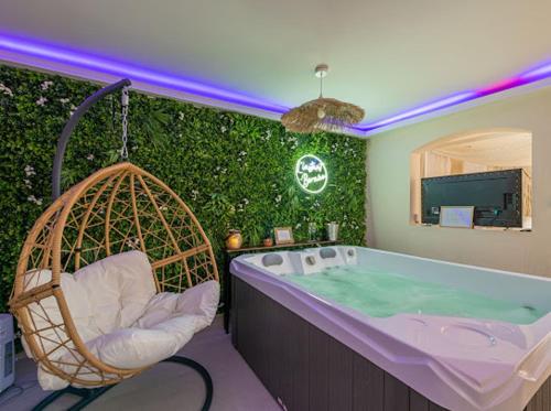 a bathroom with a tub and a chair and a green hedge at L'instant Bornéo Superbe appartement avec jacuzzi in Liancourt