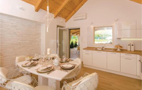 a kitchen and dining room with a white table and chairs at Beautiful Home In Seget Donji With Heated Swimming Pool in Trogir