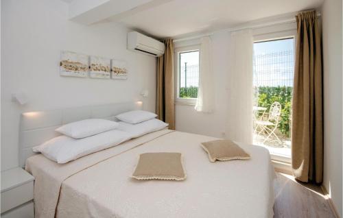 a white bedroom with a bed with two towels on it at Beautiful Home In Seget Donji With Heated Swimming Pool in Trogir
