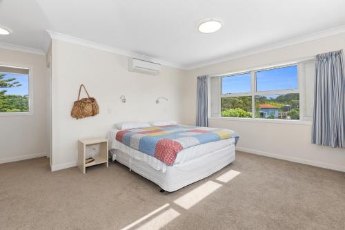 a white bedroom with a bed and two windows at Matapouri Family Retreat - Matapouri Holiday Home in Matapouri