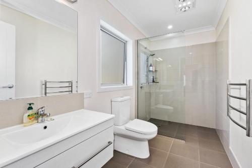 een witte badkamer met een toilet en een wastafel bij Matapouri Family Retreat - Matapouri Holiday Home in Matapouri