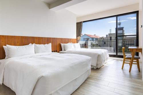 two beds in a hotel room with a large window at Kenting Sea Wall 112 in Kenting
