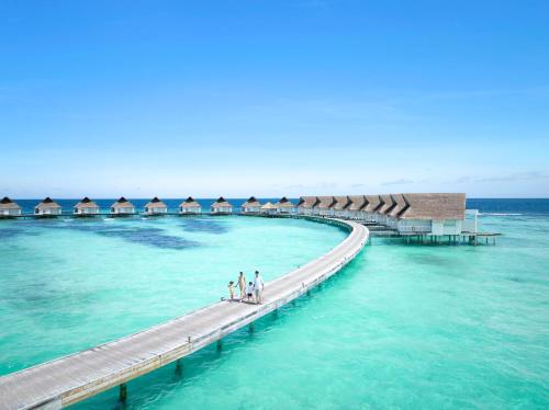 molo w oceanie z ludźmi chodzącymi po nim w obiekcie Centara Grand Island Resort & Spa w mieście Machchafushi