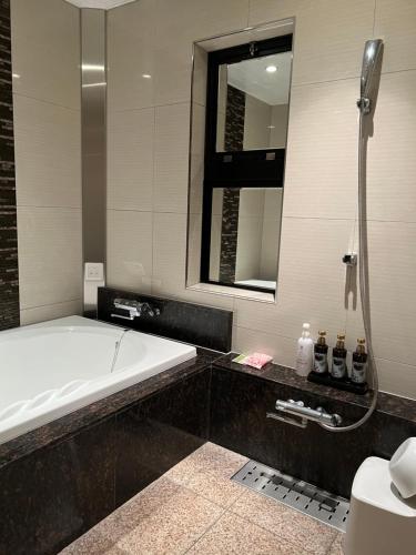 a bathroom with a tub and a toilet and a sink at HOTEL Shuffle in Tokyo