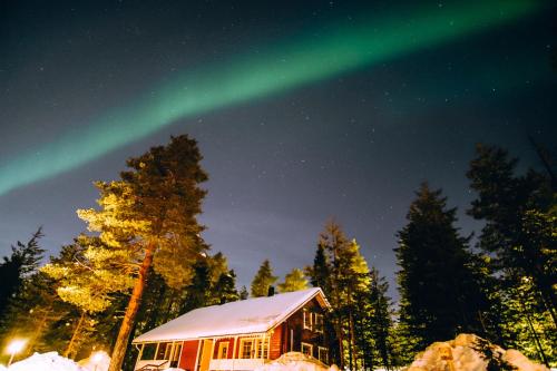 a cabin with the aurora dancing in the sky at Tilhi Chalet in Rovaniemi