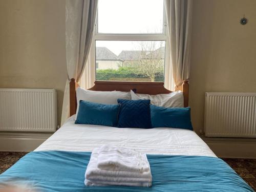 a bed with blue and white sheets and a window at Spacious Flat In a Victorian House - Free Parking in Bradford