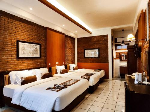 ジョグジャカルタにあるパク マス ホテルのベッド3台とキッチンが備わるホテルルームです。