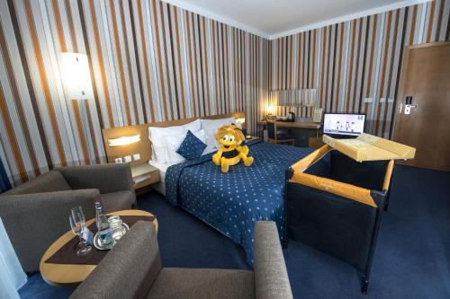 a teddy bear sitting on a bed in a hotel room at Hotel Blue Bratislava in Bratislava