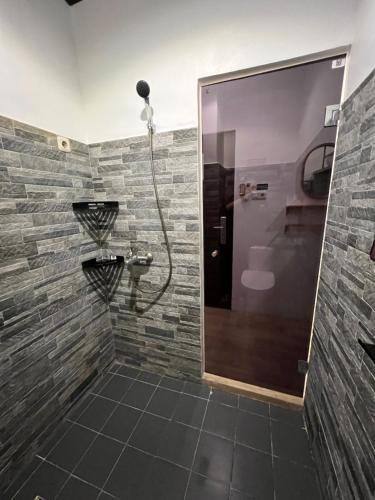 a bathroom with a shower with a stone wall at Choska Residence in Jakarta